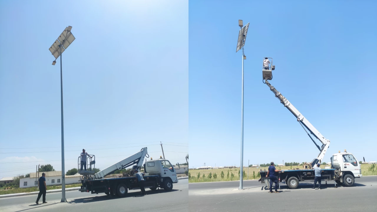 A crane erecting a tall solar street light pole on a highway