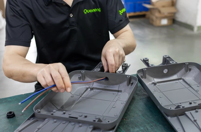 Factory worker connecting internal wiring to solar street light LED module housing