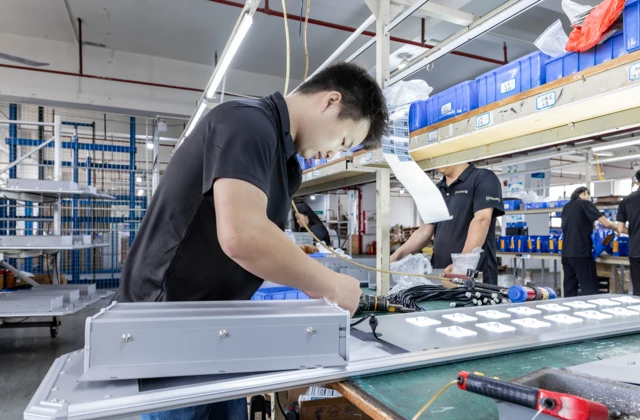 Workers assembling aluminum housing fixtures for all-in-one solar street lights on production line